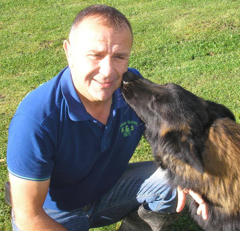 Denis Barrat reçoit une léchouille de son chien sur le terrain